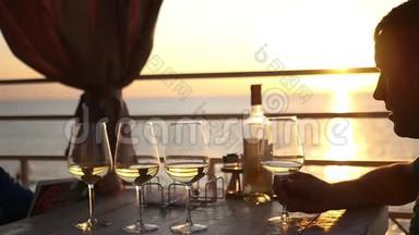 日落时分，两个朋友正坐在海边的一家餐馆里，喝着<strong>酒</strong>。 高清，1920x1080。 慢动作