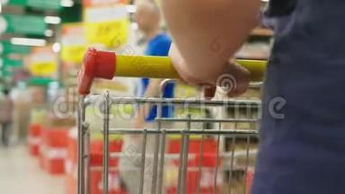 超市里的一个女人正从柜台边经过篮子。 一个女人在超市里走来走去，特写镜头。