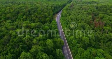 空中景色随着汽车的移动飞越公路，那穿过车道的绿色森林。 汽车沿林路行驶.. 汽车轮胎