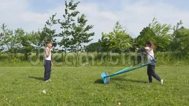 青少年男孩和女孩在草地上打<strong>羽毛球</strong>，背景是森林。 手持<strong>羽毛球</strong>拍的<strong>儿童</strong>