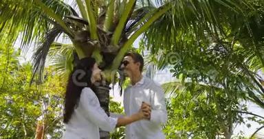 情侣站在棕榈树<strong>下</strong>亲吻热带花园，欢乐男人和女人户外