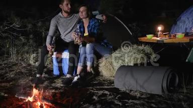 浪漫的夜晚情人在森林里搭帐篷，年轻夫妇在旅途中喝啤酒，在大自然中搭帐篷，旅游之旅