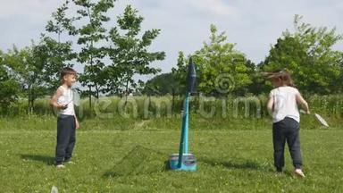 青少年男孩和女孩在草地上打羽毛球，背景是森林。 手持羽毛球拍的儿童