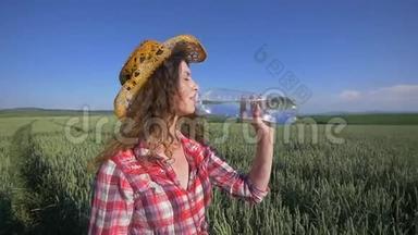 年轻女子在麦田里喝水降温