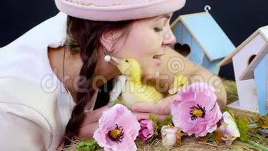 肖像，一个漂亮的年轻女人，有两条辫子，戴着一顶有趣的粉红色帽子，和小黄鸭玩耍。 工作室