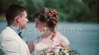 结婚纪念日。 美丽的夫妇在码头上接吻，享受他们的幸福。 结婚礼服，花束