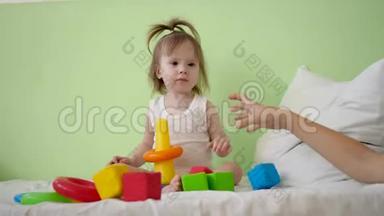 孩子和妈妈在床上玩五颜六色的立方体。 学前和幼儿园儿童的教育玩具.. 儿童玩具