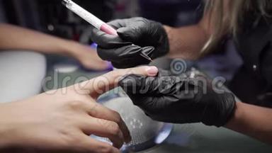 美甲师在美甲沙龙里对女孩的指甲进行修脚和延长指甲的程序