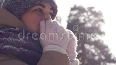 一位在户外散步的年轻女子在<strong>冬天</strong>的公园里散步时，她用手臂呼吸以<strong>保暖</strong>