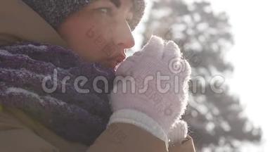 一位在户外散步的年轻女子在<strong>冬天</strong>的公园里散步时，她用手臂呼吸以<strong>保暖</strong>