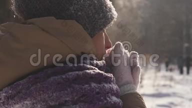 一位在户外<strong>散步</strong>的年轻女子在冬天的<strong>公园里散步</strong>时，她用手臂呼吸以保暖