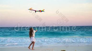在热带海滩放风筝的小女孩。 孩子在海边玩。 带沙滩玩具的儿童慢动作