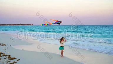 在热带海滩放风筝的小女孩。 孩子在海边玩。 带沙滩玩具的儿童慢动作