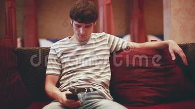 男人坐在沙发上，在智能手机上浏览互联网。 1920x1080。 高清高清