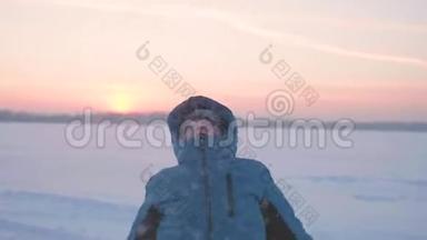 一个孩子在<strong>冬天户外</strong>玩耍，跑步，把雪扔到顶部。 美丽的日落。 <strong>户外运动</strong>
