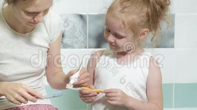 妈妈轻轻地刷牙她心爱的女儿的牙齿一个小女孩和她的母亲轻轻地清洁牙齿后，吃。