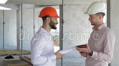 两位建筑工人<strong>正在施工</strong>的大楼里看着数码平板电脑
