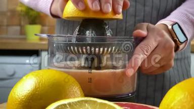 厨房里的女人用电动榨汁机榨柑橘汁。