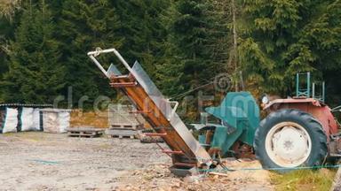 村里的小锯木厂。 一台拖拉机和一个锯架在<strong>树林</strong>里，旁边是切割和<strong>包装</strong>的原木