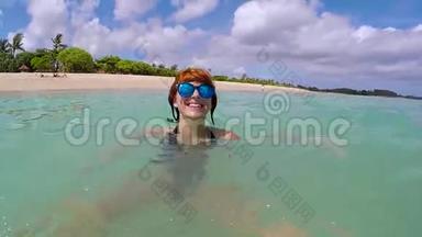 快乐兴奋的女人带着<strong>蓝色</strong>的眼镜在海洋中玩得很开心，<strong>展示</strong>了她的腿和微笑。 慢动作，热带岛屿
