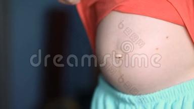 年轻的孕妇展示她的大肚子，未来的孩子蓝色的色调，稳定的凸轮，慢镜头
