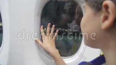少女告别，挥手向窗前的飞机<strong>航空飞机</strong>生活方式概念。 年轻的女孩
