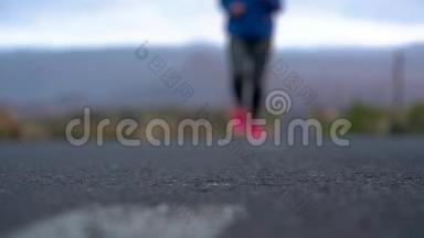 跑鞋-在山区的沙漠道路上系鞋带的女人。 慢动作