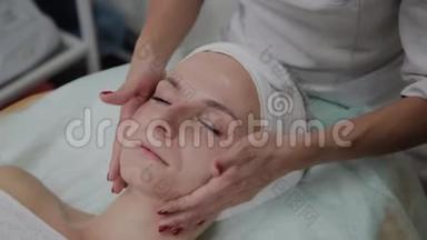 专业美容师给女孩脸上涂保湿霜。