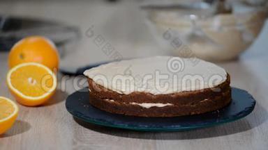 糖果师把奶油放在蛋糕的顶部。 面包师平滑蛋糕与奶油糖霜。