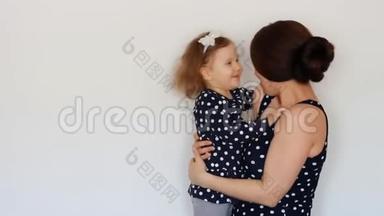 快乐的母亲抱着女儿，拥抱亲吻，表达<strong>母爱</strong>。抱着孩子的年轻女子