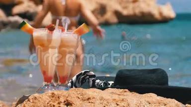 埃及海滩上的热带<strong>鲜榨果<strong>汁</strong></strong>、帽子和眼镜架在红海边的岩石上