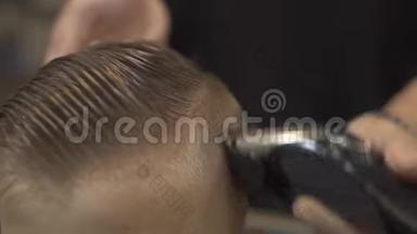儿童理发师用理发机把小男孩剪得很近。 有电器的儿童发型