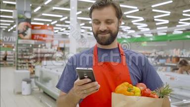 微笑超市员工使用手机，拿着购物袋在超市