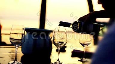 在令人惊叹的日落时分，在海滩餐厅的海景中，在玻璃杯中倒入白<strong>酒</strong>。 1920x1080