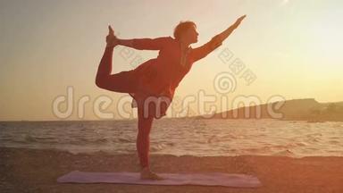 在海滩上日落时瑜伽。 做瑜伽，做体式的女人