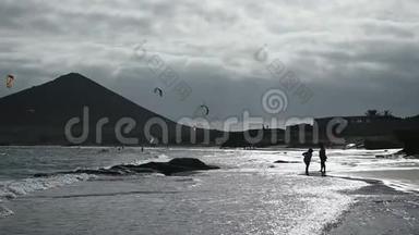 许多五颜六色的风筝在海滩上和风筝冲浪在大风天乘风破浪