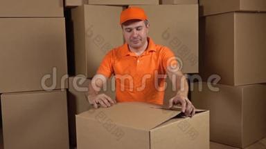 仓库工人穿橙色制服解开大纸箱，装满软包装材料。 防震容器。 多重