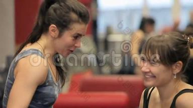 两个女人在<strong>健身房</strong>锻炼后放松和交谈。 两个女孩在<strong>健身房</strong>聊天。 女孩们在运动机器之间大笑