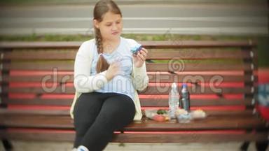 亲近一个可爱的小胖女孩，在蛋糕和蔬菜之间潜水，坐在咖啡馆的长凳上，概念是一个