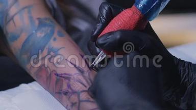 专业的纹身艺术家在一个年轻女孩的手上做一个纹身`慢动作。 纹身师在工作室做纹身