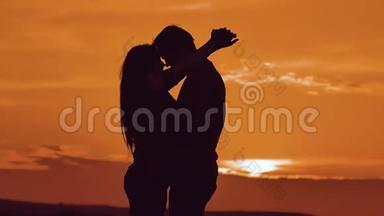一对相爱的情侣在夕阳下拥抱剪影。 家庭爱情概念爱。 一对男女的爱情剪影