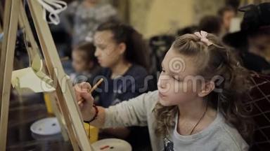 坐在画架上的漂亮少女在一所<strong>艺术学校</strong>画一幅画。 儿童专业<strong>艺术学校</strong>