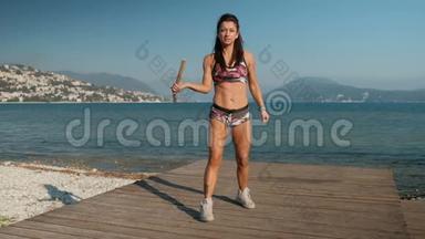 一个漂亮的女人在一个海上码头熟练地转动木制双节。