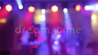 舞蹈的背景是模糊的人们在夜总会跳舞。 蓝色和紫色