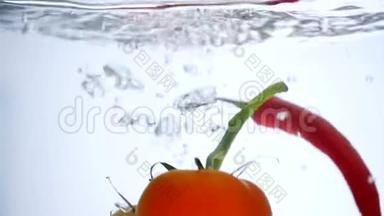 新鲜西红柿和辣椒<strong>落入</strong>清水中的特写镜头，白色背景上有大的水花。健康饮食