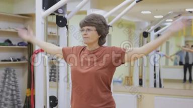 老年妇女伸展身体，在健身室做理疗。 健康体操。 活跃的老年人。
