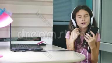 少女在音乐耳机里跳舞唱歌.. 女生在网上听音乐，在室内跳舞唱歌