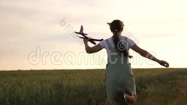 快乐女孩带着玩具飞机在麦田里奔跑。 孩子们玩玩具飞机。 少年梦想飞翔，成为一名