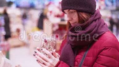 一位年轻的美女在商店里走来走去，挑选圣诞装饰品和装饰品来庆祝新年和圣诞节