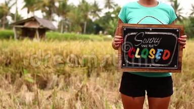 女人的手与封闭的标志板在热带自然背景。 巴厘岛。